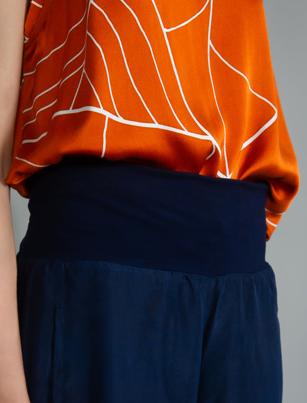 Waistband detail. Super lightweight 100% habutai silk pant in navy blue, with wide leg, drawstring gather at the ankle, a deep jersey waistband with a drawstring and patch pockets on the back.