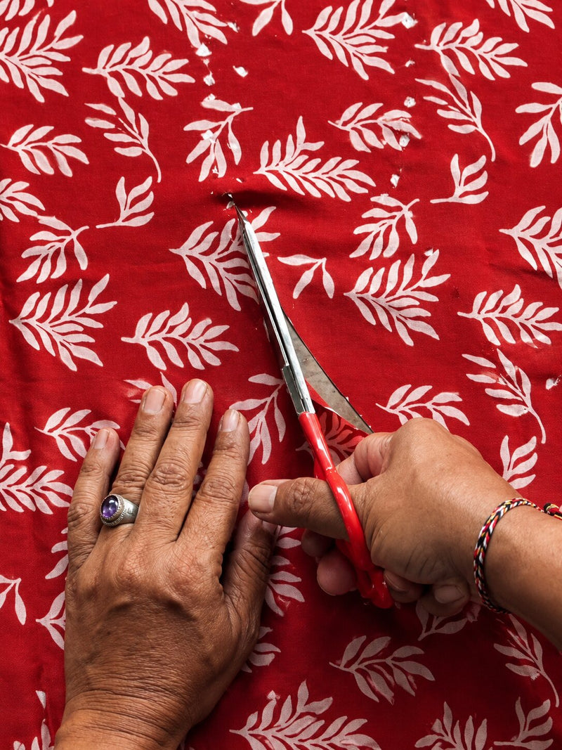 Hands cutting silk along a paper pattern