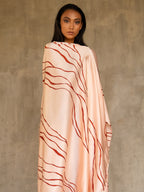 A woman wearing a pink champagne colored silk sarong batik with a geometric kintsugi pattern, tied in a knot at the waist. Handmade in Bali