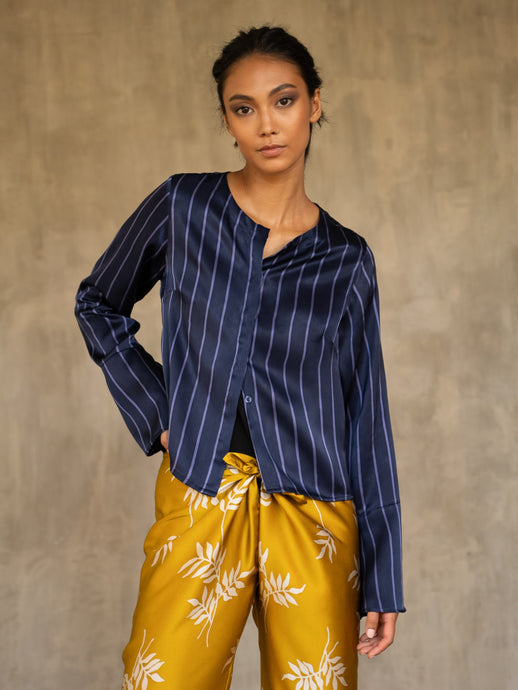 woman short jacket made in silk batik with stripes motif blue and light blue wear on top of a long silk pant yellow gold with withe floral motif