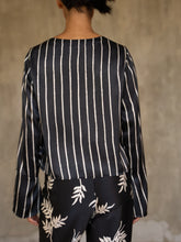 Load image into Gallery viewer, woman wearing short silk jacket black and white on a silk black pant with floral motif
