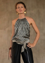 Load image into Gallery viewer, A female model wearing a steel grey satin silk halter top with a geometric leaf batik pattern and a matching silk long pant black with a grey lines motif produced in Bali

