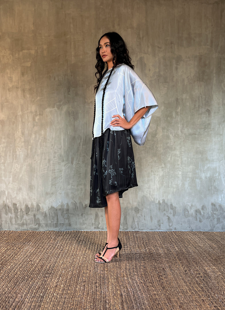 woman silk satin top hand painted in Bali in batik style and dark grey skirt with flower pattern