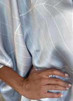 detail of a woman silk satin top hand painted in Bali in batik style and dark grey skirt