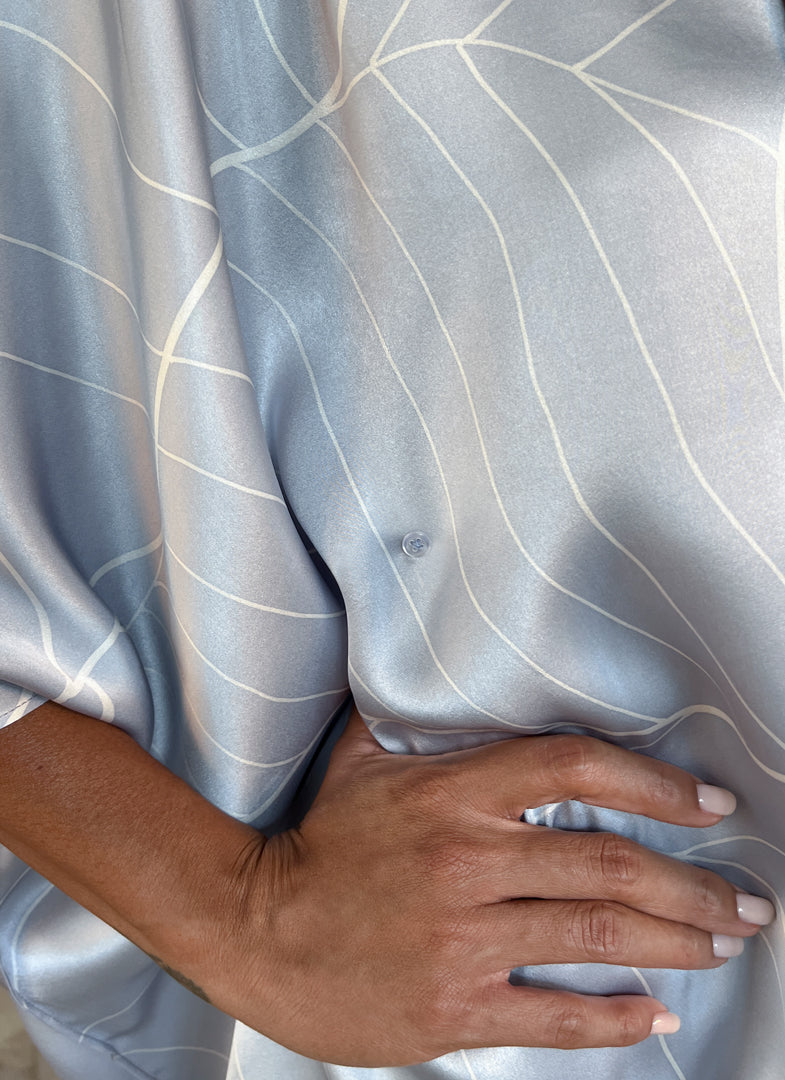 detail of a woman silk satin top hand painted in Bali in batik style and dark grey skirt